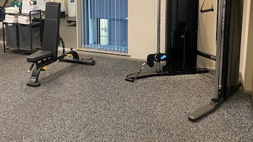 A gym with exercise equipment, a water dispenser, and a desk with a chair.