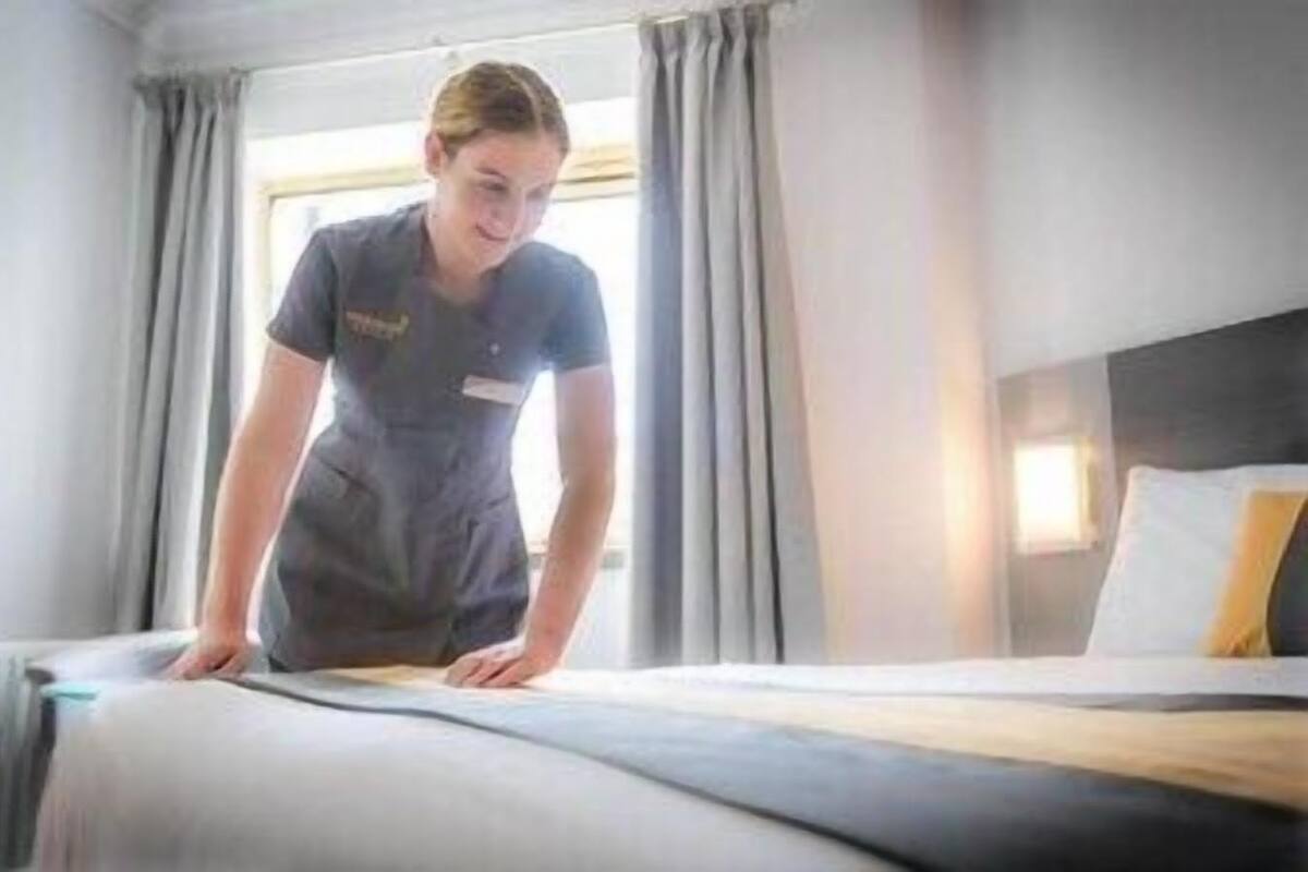 A hotel room with a bed, curtains, and a window.