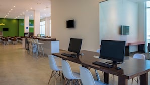 Una sala de conferencias moderna con una larga mesa, varias sillas y dos monitores.