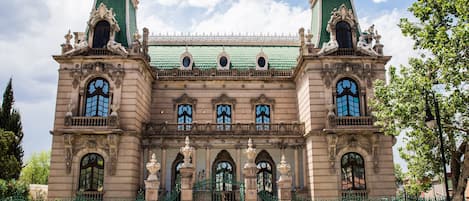A historic building with ornate architecture, large arched windows, and a green roof.