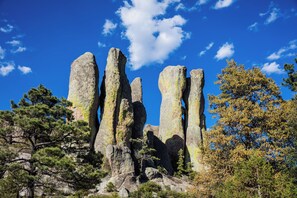 Formación rocosa natural con grandes rocas verticales y árboles circundantes.