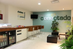 A reception area with a counter, seating, a refrigerator, and a wall with signage.