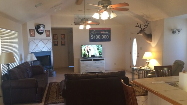 A living room with a fireplace, a television, and a ceiling fan. - Amistad Lake House Del Rio Tx (Del Rio)