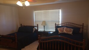 A bedroom with two wooden beds, a ceiling fan, and a window with blinds. - Amistad Lake House Del Rio Tx (Del Rio)