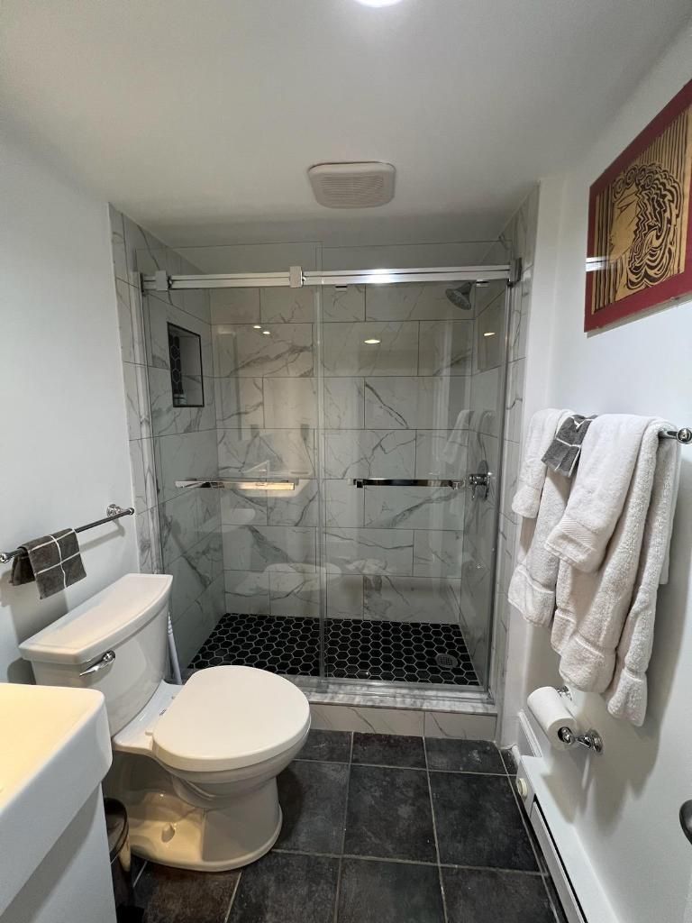 Une salle de bain comprenant des toilettes, un espace douche et un porte-serviettes.