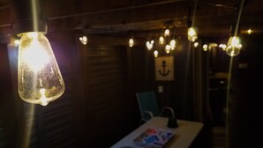 Ein schwach beleuchteter Raum mit Tisch, Stühlen und hängenden Lampen.
