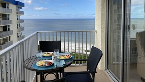 Een balkon met een ontbijttafel met uitzicht op de oceaan.