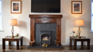 A living room with a fireplace, two lamps, and framed pictures on the walls. - The Grange, Portrush. Deluxe holiday home, 8 beds, up to 12 guests, 6 bedrooms.  (Portrush)