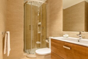 Ein modernes Badezimmer mit Duschkabine aus Glas, einer weißen Toilette und einem Waschtisch mit Spiegel.