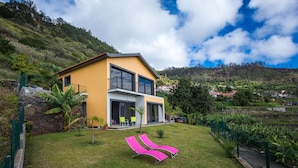A modern two-story house with a yellow exterior, large windows, and a balcony. - Super OCEAN VIEWS - Modern 2 Bed Apartment Stylishly Furnished (Arco da Calheta)