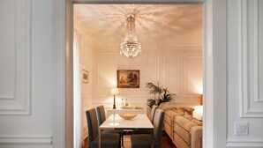 A dining area with a chandelier, a table with chairs, a sofa, and a lamp. - Charming apartment (Cascais)
