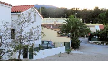 A residential area with a white building, a parked car, and a palm tree.