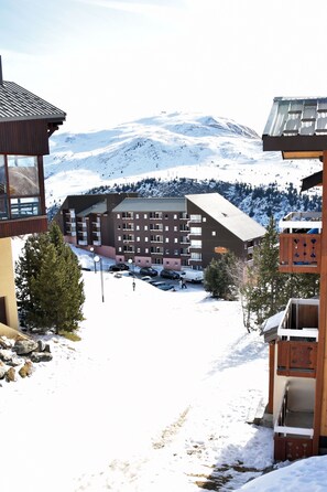 Una località montana innevata con un hotel a più piani, balconi e una seggiovia sullo sfondo.