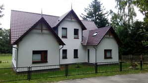 A two-story house with a tiled roof and a fenced yard. - Welcome to our apartments of Villa Wald-Eck (Apartment 2)  (Ückeritz)