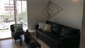 Un salon moderne avec un canapé noir, une petite table et un élément décoratif mural.