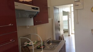Une cuisine compacte équipée d’un four encastré, d’un évier et d’un égouttoir.