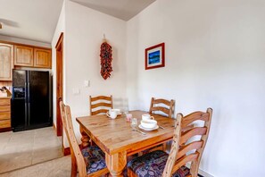 A dining area with a wooden table and chairs, a hanging decorative item, and a framed picture on the wall. - Super Ski Pad - True Ski-In/Ski-Out Retreat. Private Hot Tub. Walk to Adventure (Breckenridge)