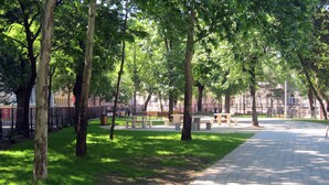 A park with trees, benches, and a paved walkway.