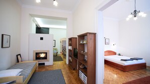 A cozy living room with a fireplace, a sofa, a bed, and wooden shelving.