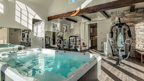 A home gym with exercise equipment, a hot tub, and a stone wall. - Gorgeous Colorado Farmhouse Getaway in Forest, yet 10 min from town: NO EVENTS (Colorado Springs)