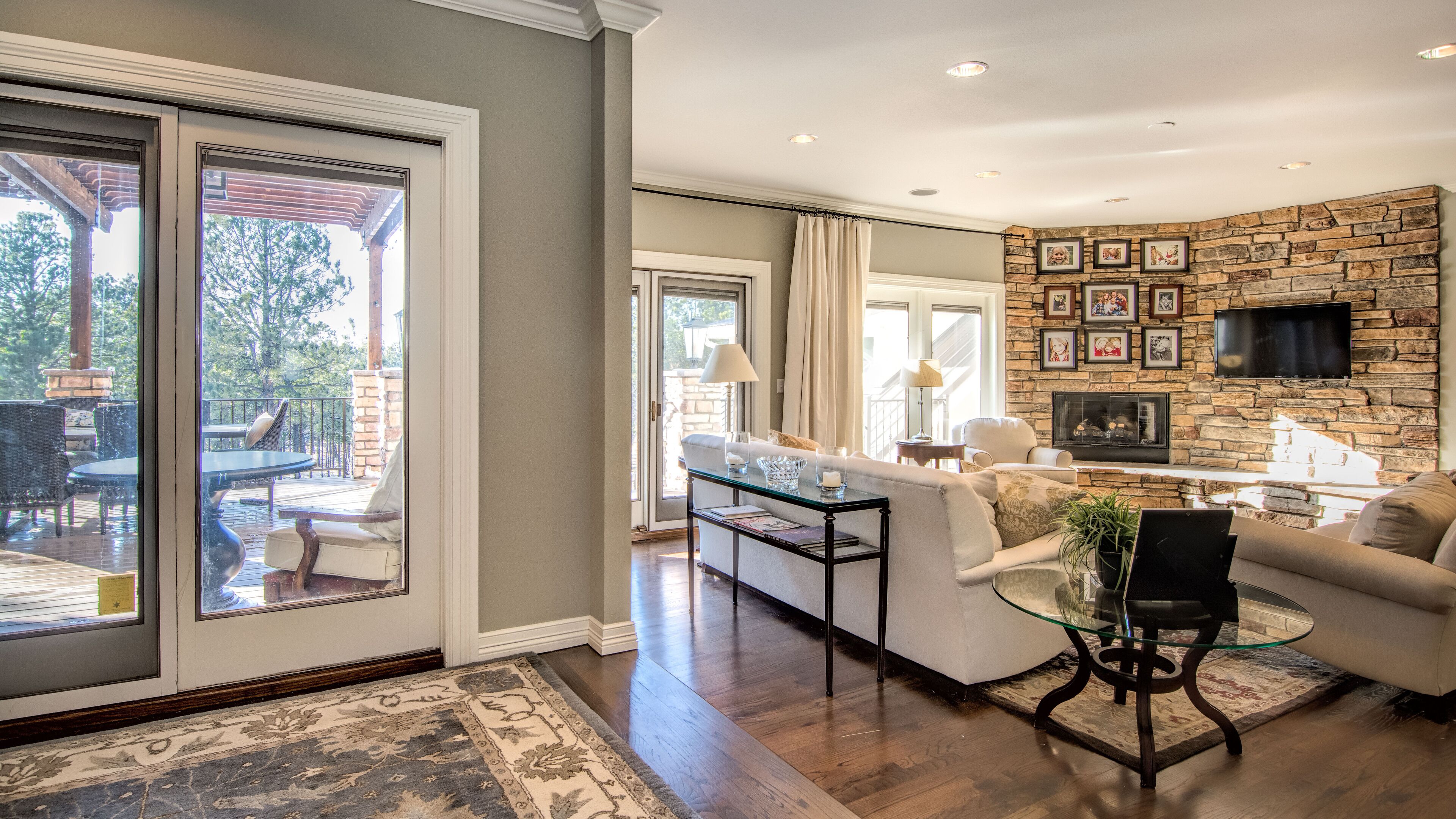 A spacious living area with a stone fireplace, a glass coffee table, and a comfortable seating arrangement.