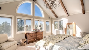 A bedroom with large windows, a wooden ceiling, a bed with floral bedding, a dresser, and a chair. - Gorgeous Colorado Farmhouse Getaway in Forest, yet 10 min from town: NO EVENTS (Colorado Springs)