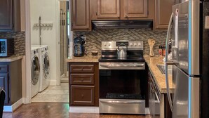 Een moderne keuken met een inbouwoven, een koelkast van roestvrij staal en een koffiezetapparaat.