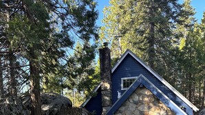 A stone house with a blue roof, a chimney, and a wooden door. - Adorable Mountain Getaway (Shaver Lake)