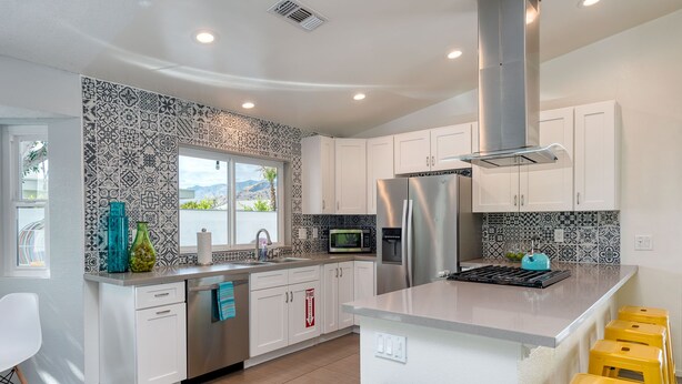 A modern kitchen with white cabinets, a stainless steel refrigerator, a microwave, and a gas stove. - Best Views! Golden Girls themed House. Pool and Spa! (Palm Springs)