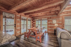 L’intérieur d’un chalet en bois comprend une table à manger, des bancs, un canapé et de grandes fenêtres.