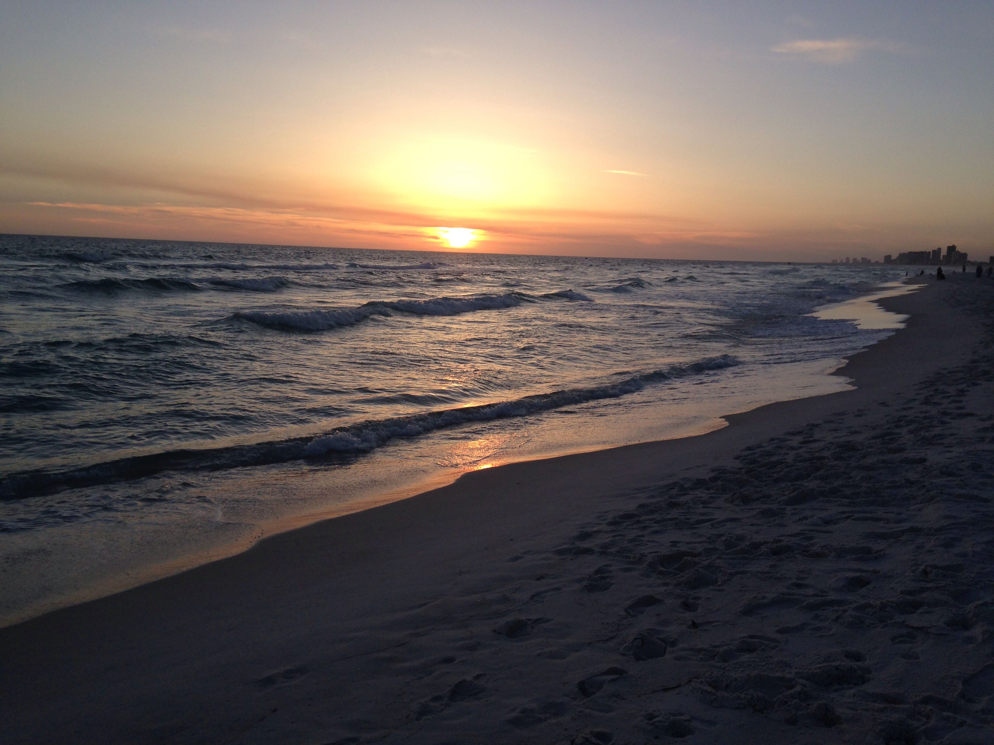 Una playa con olas y un atardecer.