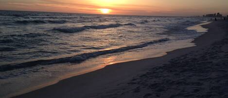 Una playa con olas y un atardecer.