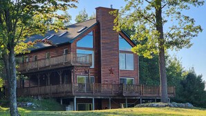 Een vakantiehuisje van hout met een balkon en een groot raam.