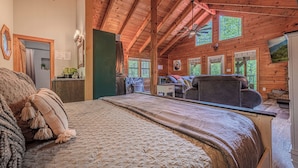 Een slaapkamer in een blokhut met een groot bed, een bureau en een stoel.