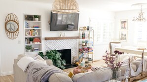 A living room with a sofa, a fireplace, a bookshelf, and a television. - The Family Beach House  (San Diego)