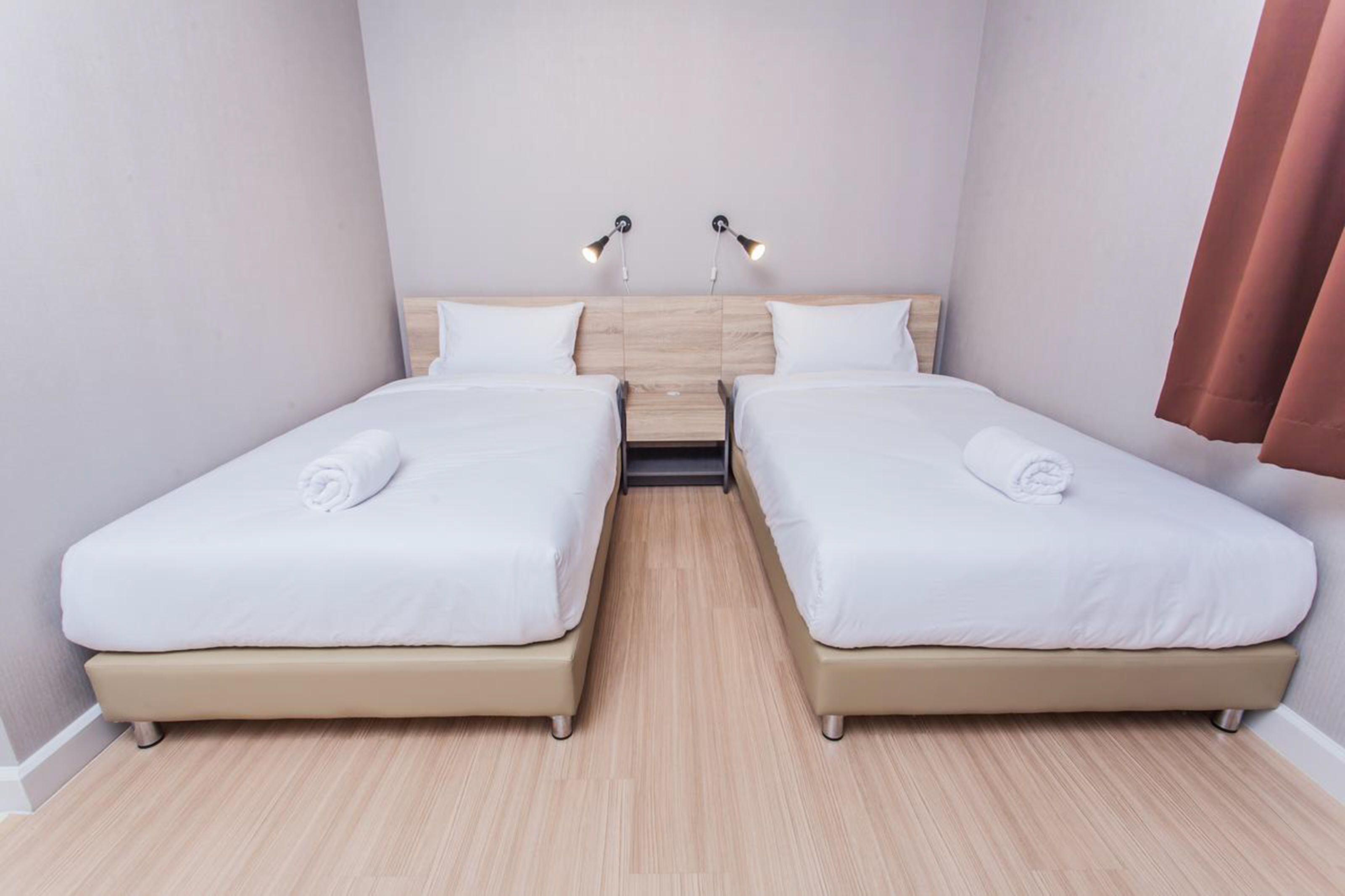Una habitación con dos camas individuales, un cabecero de madera y dos lámparas de noche.