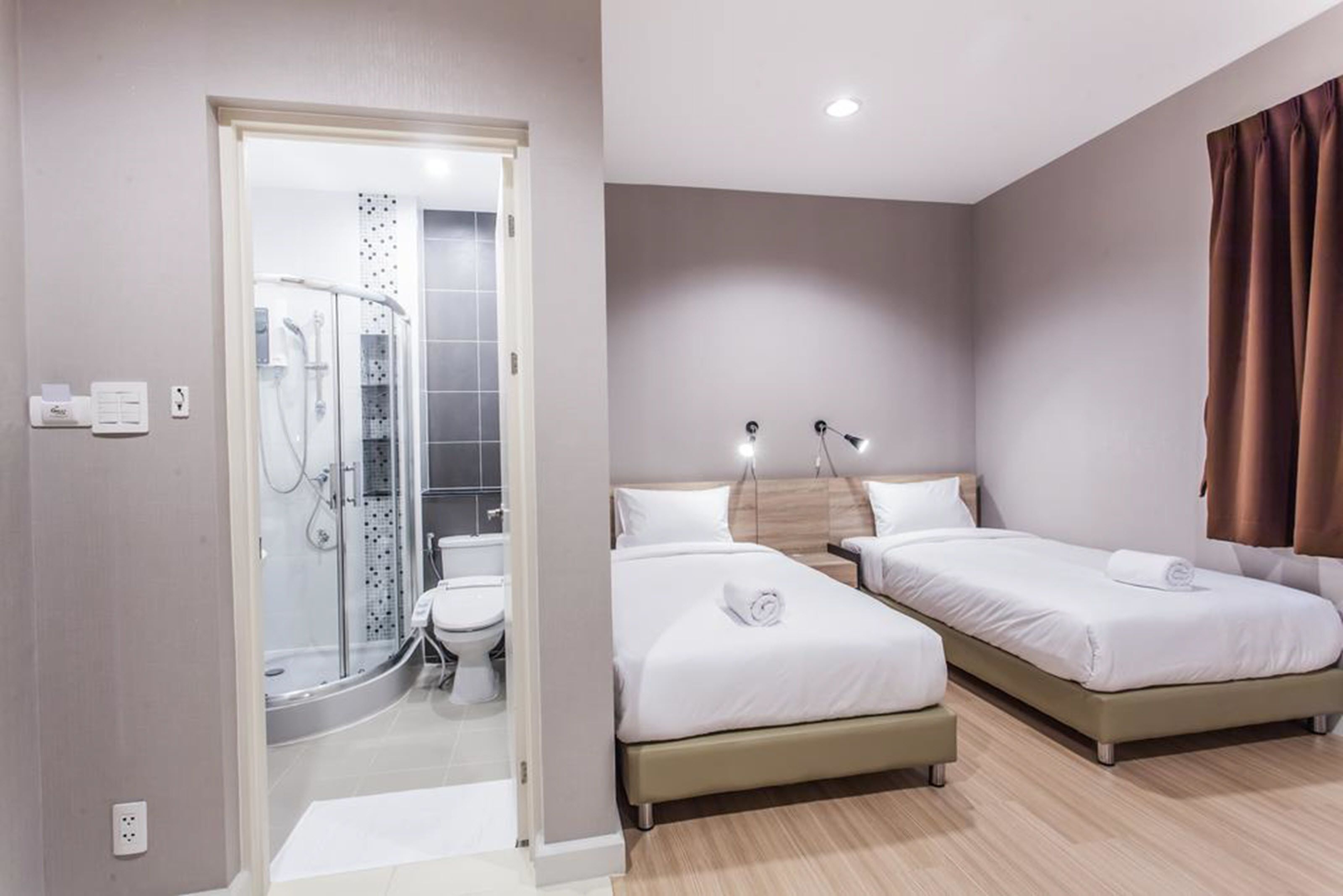 Una camera d'albergo con due letti, un angolo doccia e una piccola zona salotto.
