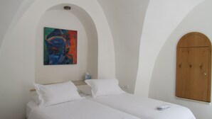 A room with two beds, a wooden wardrobe, and a colorful abstract painting on the wall. - Legatia (Jerusalem)