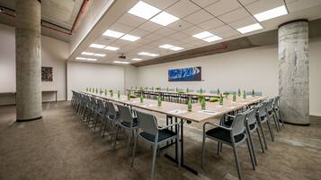 Un salón de conferencias con una larga mesa, sillas y botellas verdes.