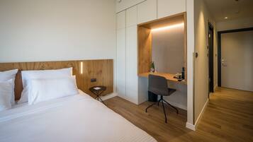 A hotel room with a bed, a desk, and a chair.