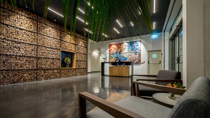 A modern lobby with a stone wall, a reception desk, and seating areas. - La Cappella Hotel (Haifa)