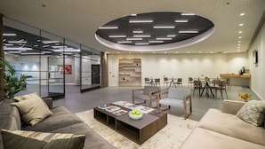 A modern living room with a coffee table, sofas, and a dining area with chairs and a table. - La Cappella Hotel (Haifa)