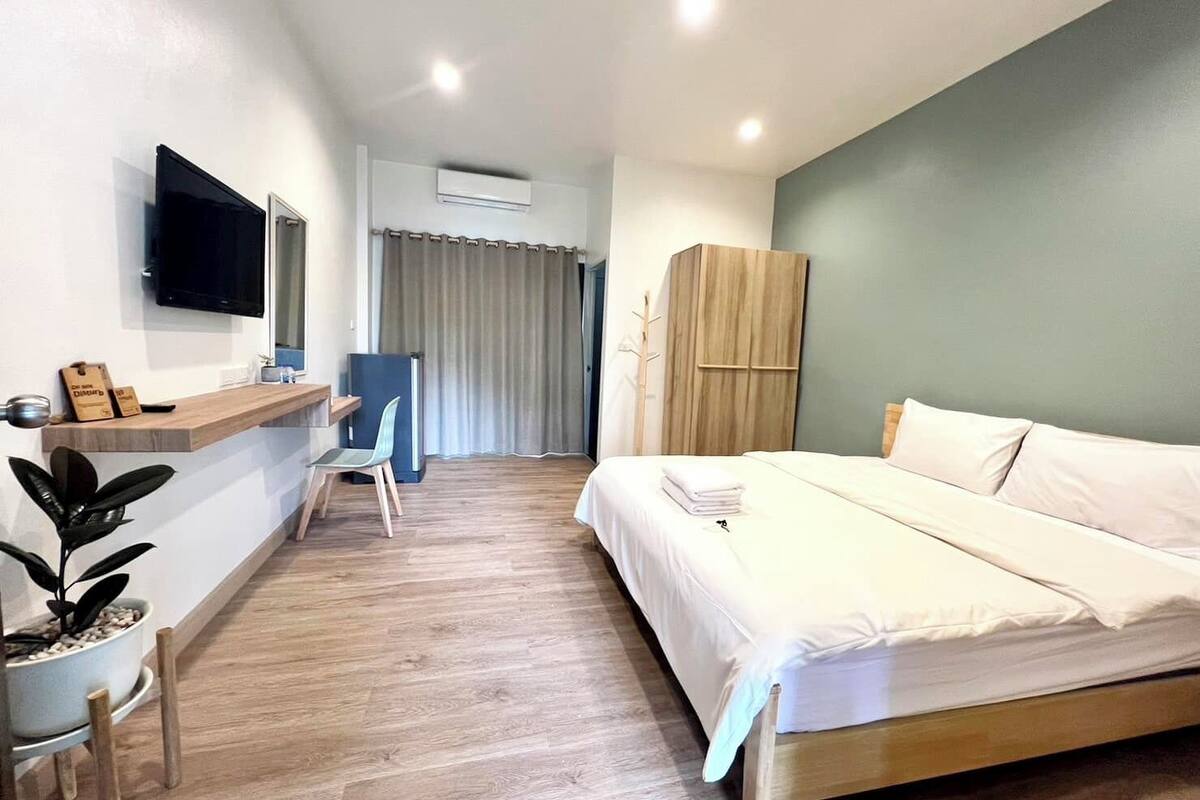 Hotellihuone, jossa on sänky, työpöytä, tuoli, televisio ja vaatekaappi.