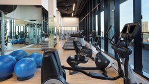A gym with cardio equipment, exercise balls, and large windows.