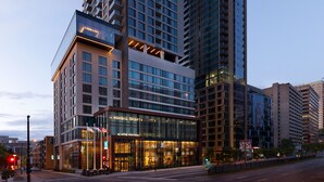 A modern hotel with a glass facade, multiple floors, and a prominent entrance with illuminated signage.