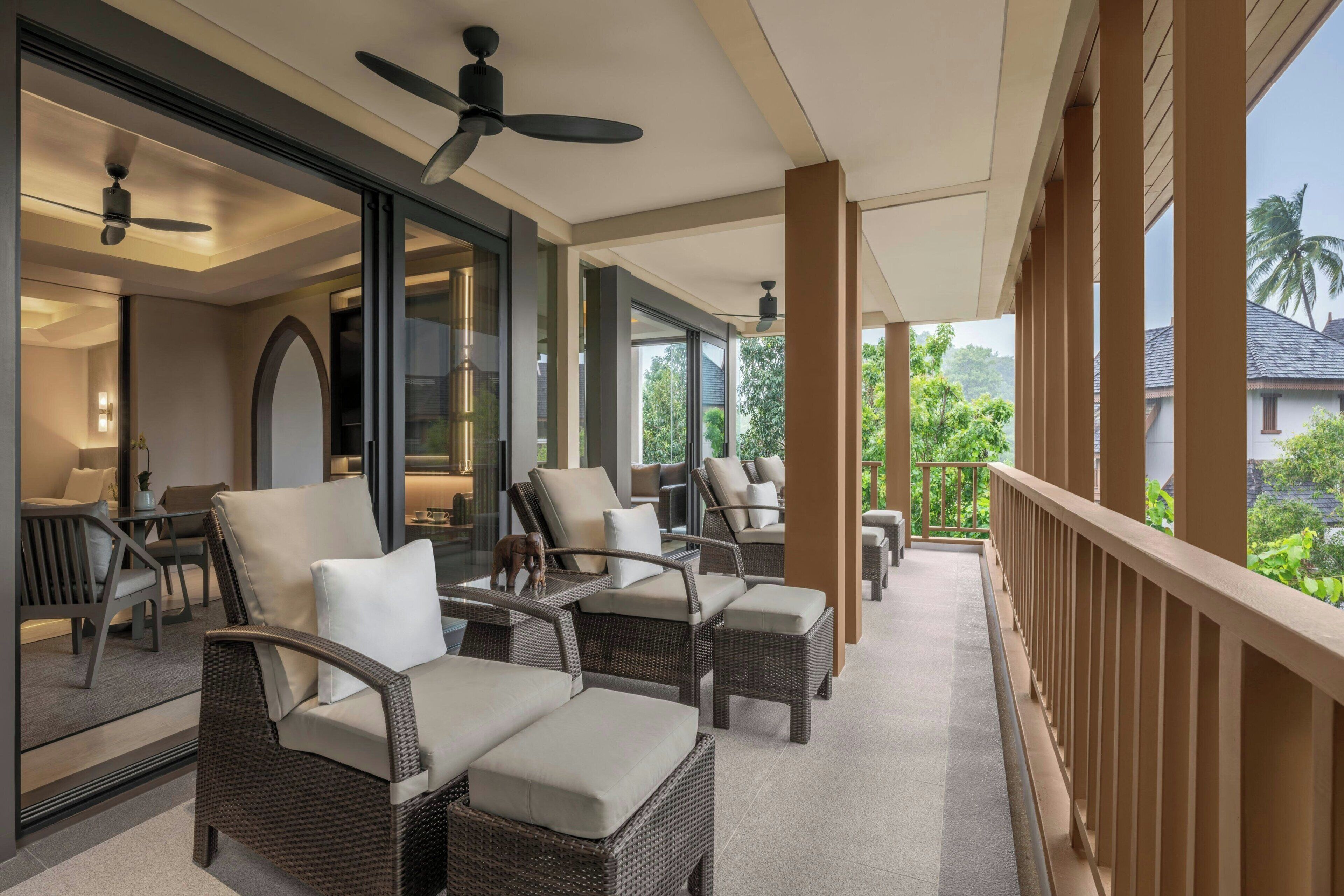 A covered outdoor seating area with wicker furniture and ceiling fans.