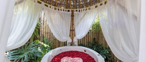 A hot tub surrounded by white drapes and bamboo.