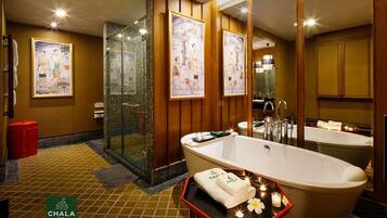 A hotel bathroom with two large tubs, a glass shower enclosure, and artwork on the walls.