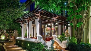 An outdoor seating area with a pergola, a water feature, and decorative statues. - Chala Number 6 Hotel (Chiang Mai)