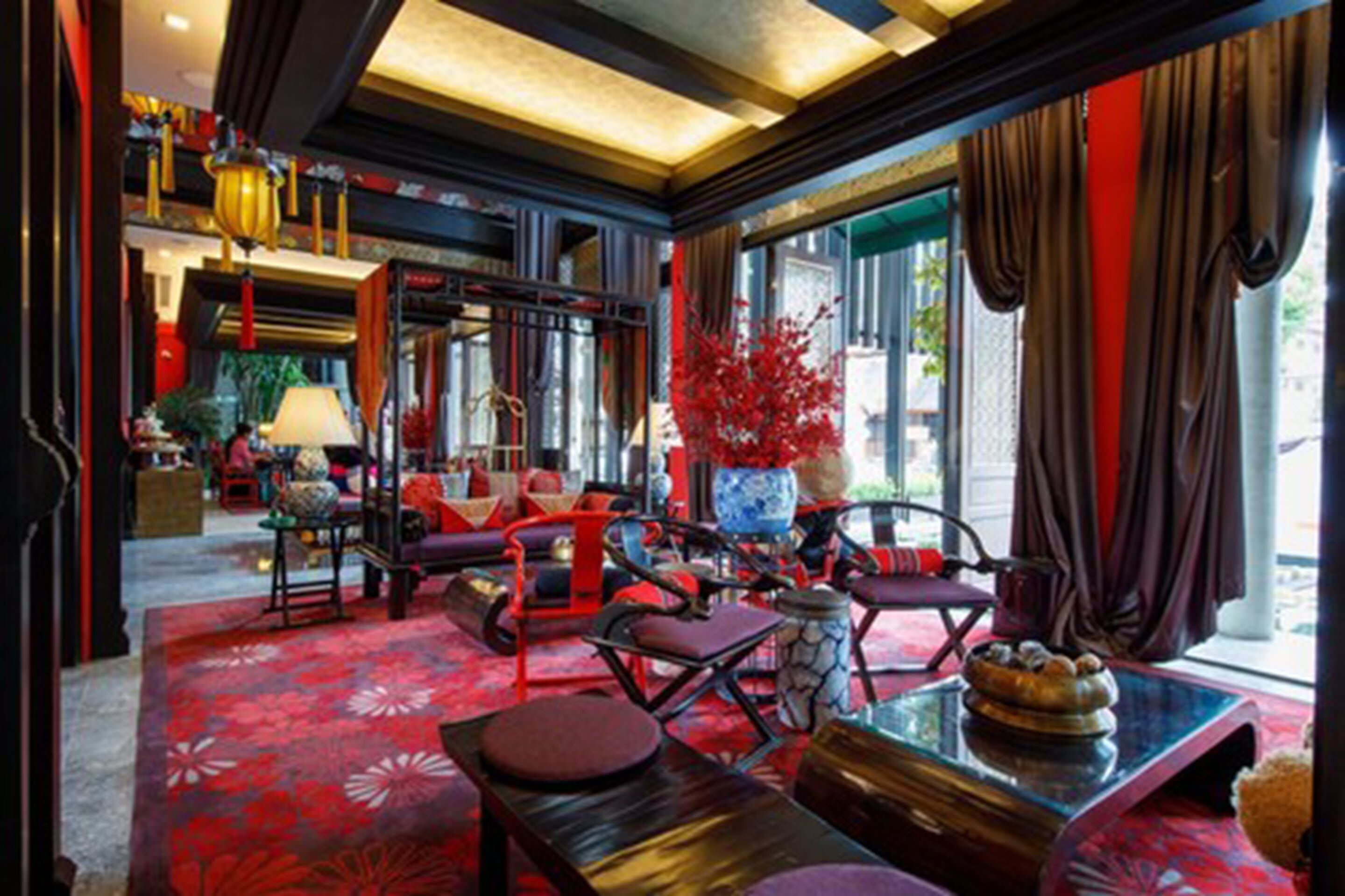 Un interior tradicional con muebles rojo y negro, un jarrón grande y vistas a la calle.